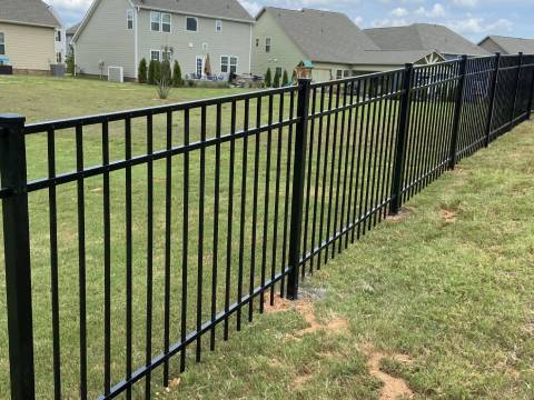 A fence that is in the grass near some houses.