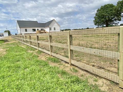 A fenced in field with a house behind it.