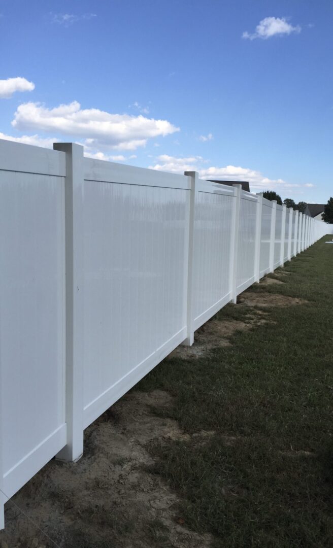 A white fence with grass in the foreground.