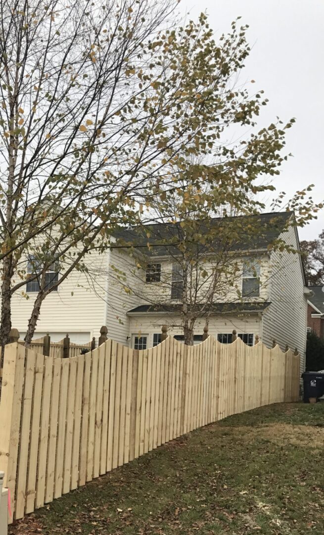 A house with a fence and trees in the background