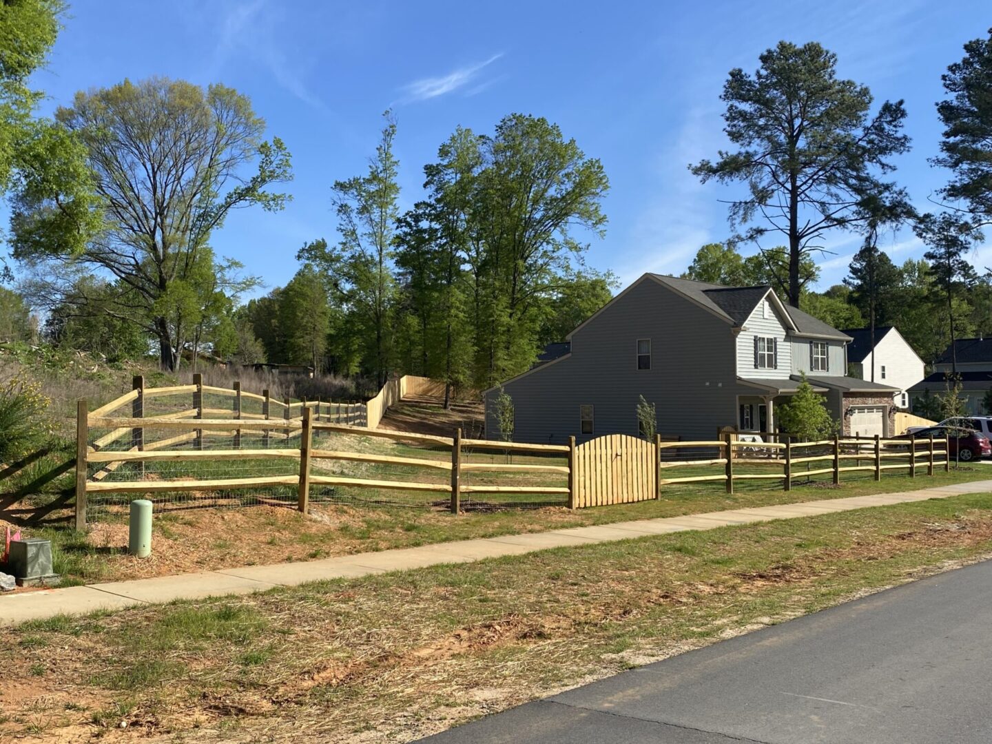 A fence that is in the grass near some trees.