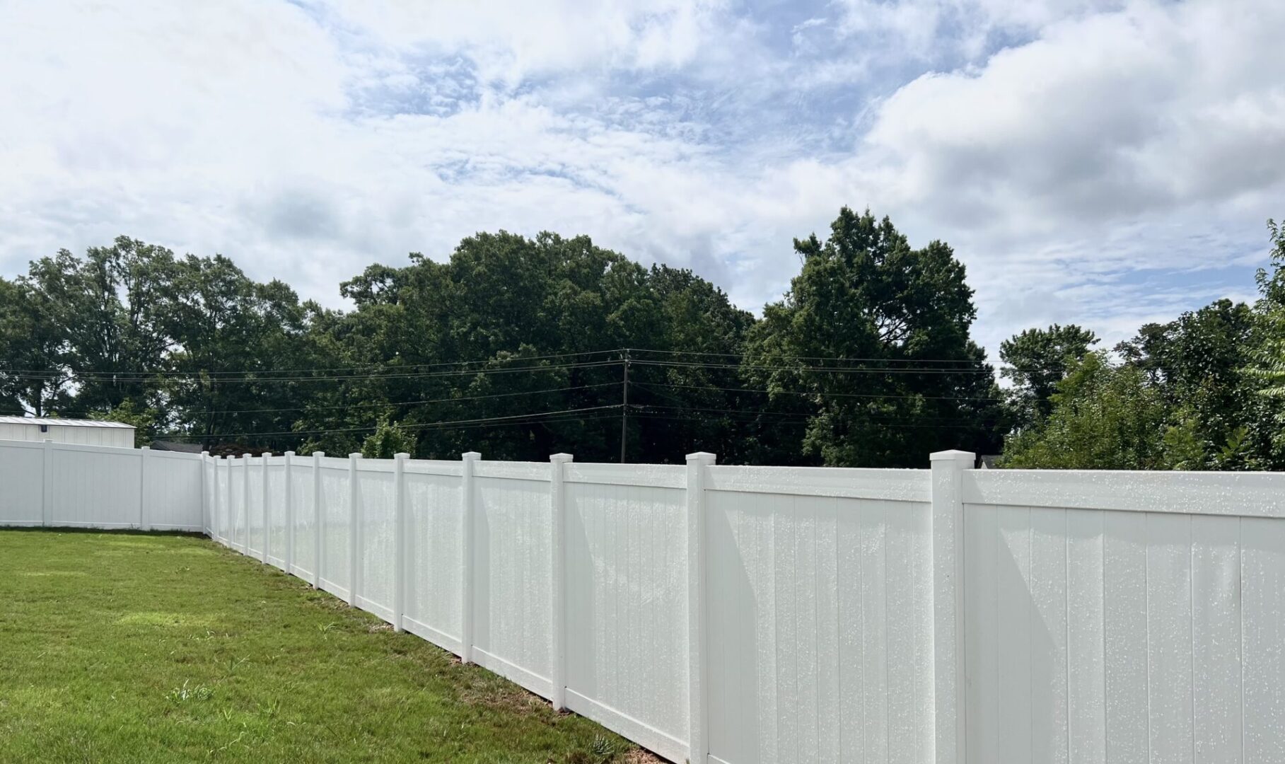 A white fence with trees in the background