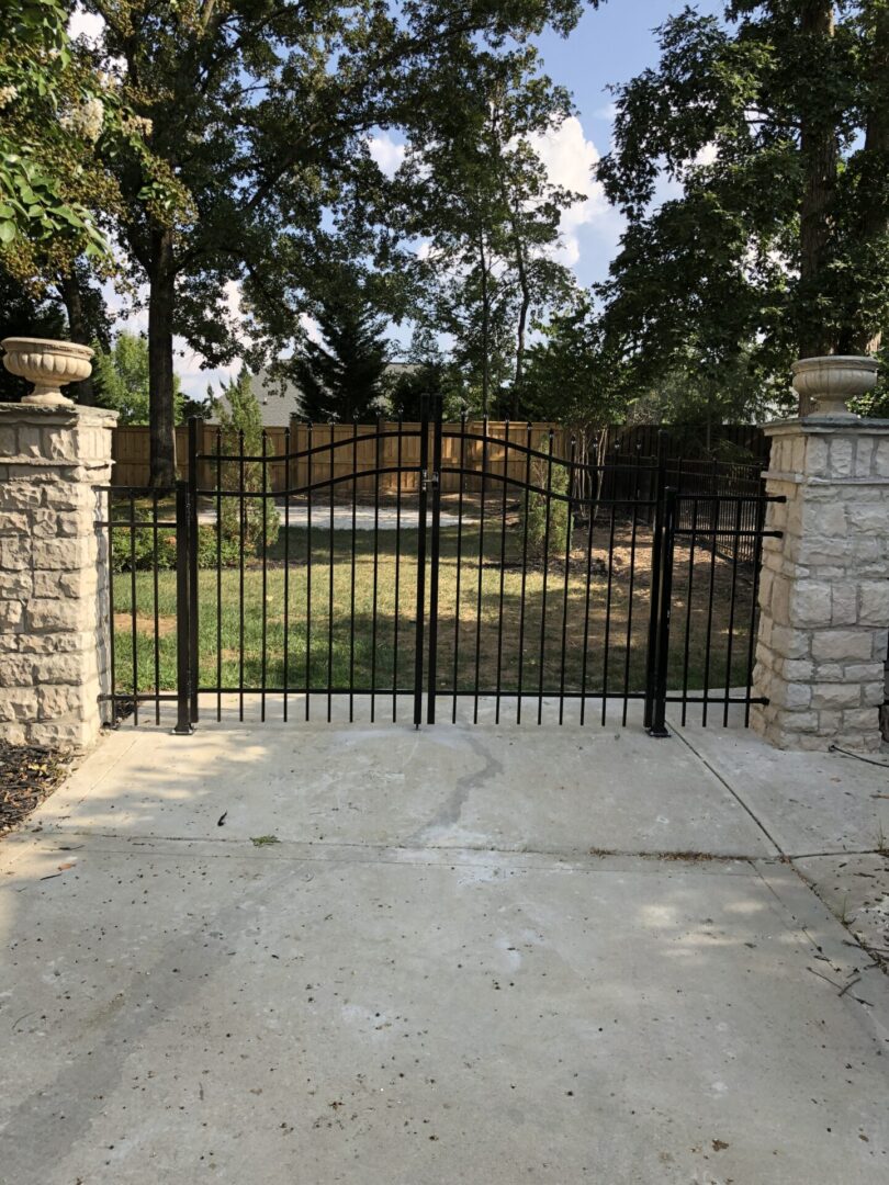 A driveway with stone pillars and wrought iron gates.