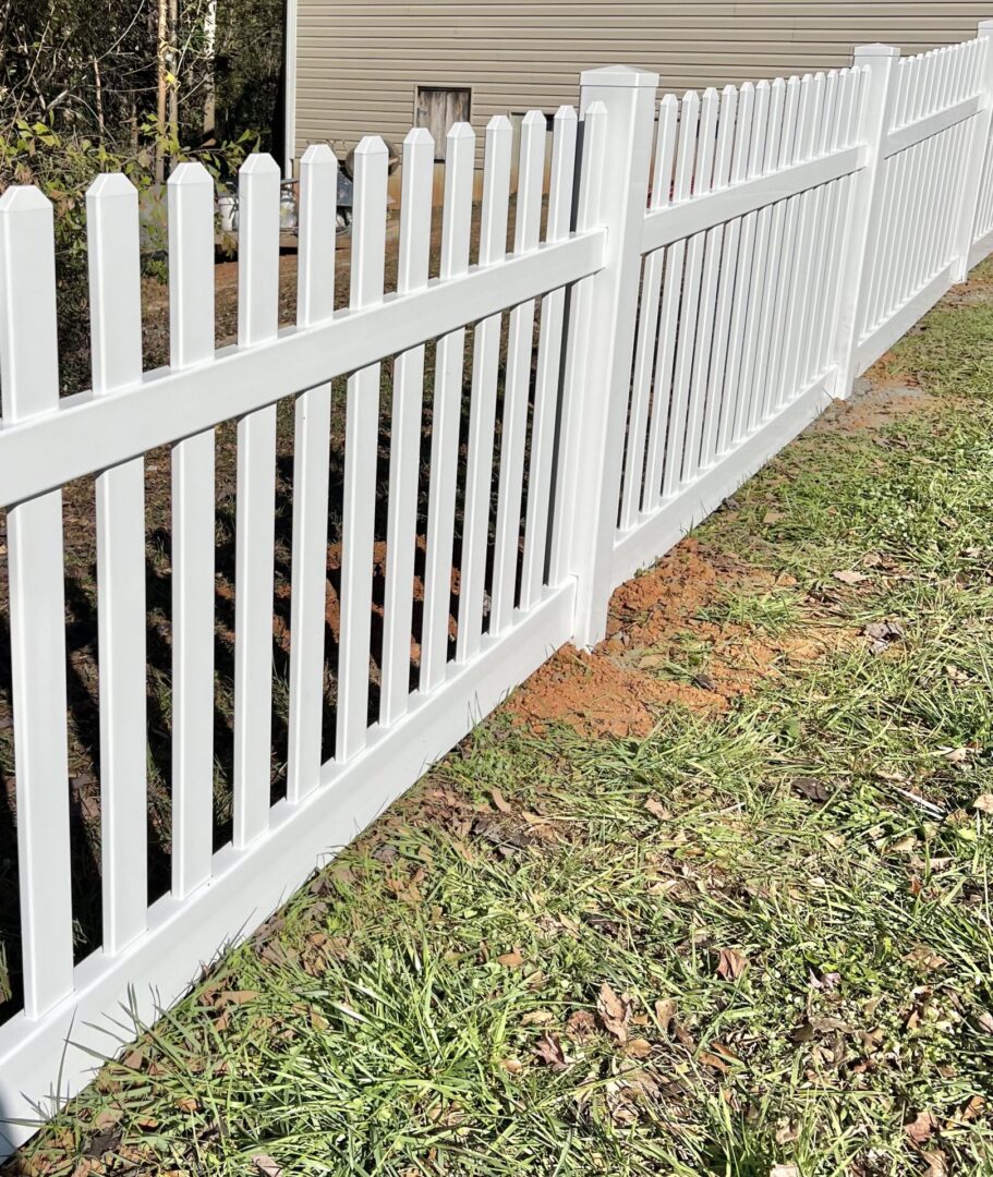 A white fence with a dog in the grass.