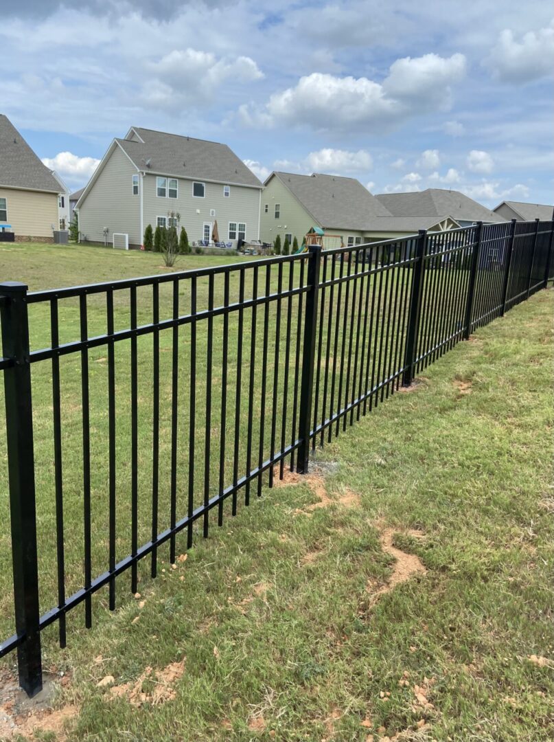 A fence that is in the grass near some houses.