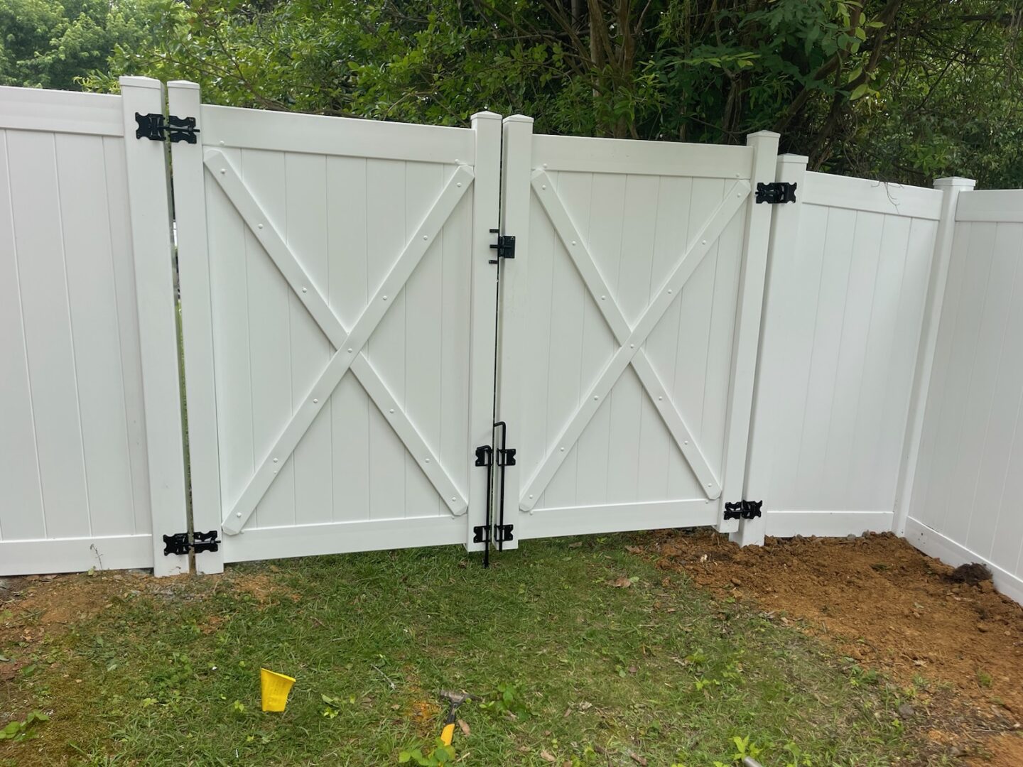 A white fence with two black metal gates.