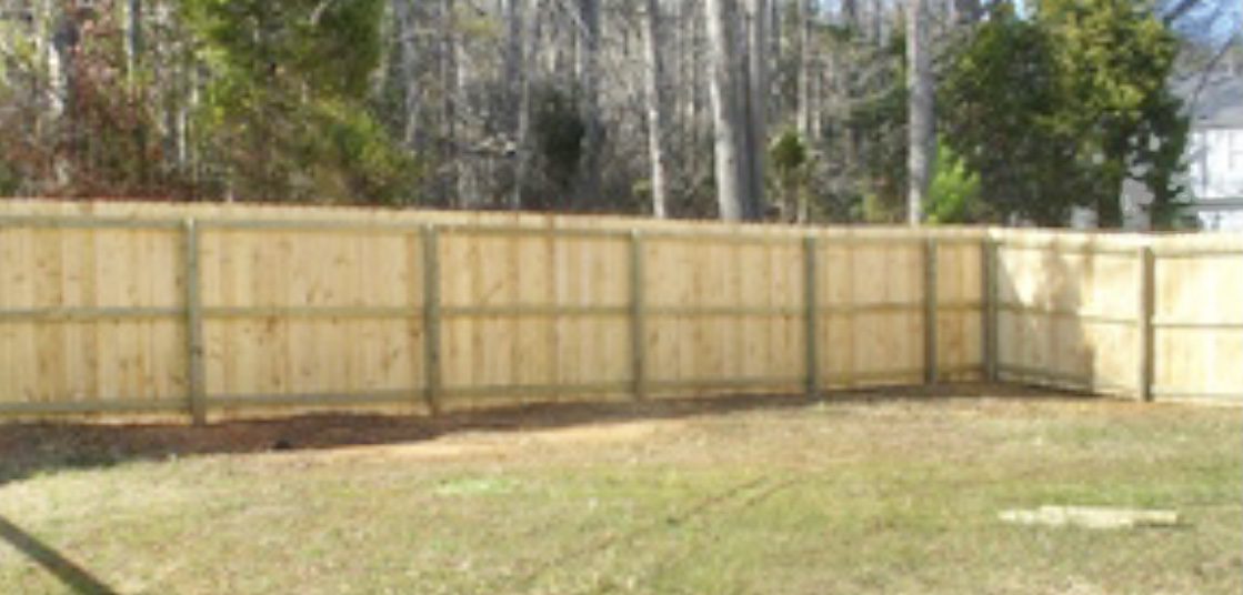 A fence that is made of wood and has trees in the background.